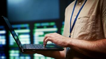 IT developer using laptop to monitor server farm security to protect information access, making sure virus protection software is updated and hackers trying to penetrate systems are rejected, close up photo
