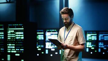 Repairman doing annual system servicing, imputing data on tablet of required upkeeping in server racks housing advanced data storage infrastructure supporting critical IT workloads photo