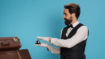 Hotel concierge presents service bell, showcasing hospitality concept and ringing for assistance. Classy bellboy or doorman helping with suitcase, luxurious formal occupation in tourism sector. photo