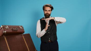Hotel concierge does timeout symbol in studio, asking for a break working in hotel and tourism industry. Elegant doorkeeper in formal attire indicating pause gesture with hands, professional job. photo