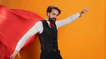 Confident waiter with red hero cape posing as a superhero on camera, determined to serve clients. Superhuman restaurant employee serving food and drinks, hero character costume with mantle. photo