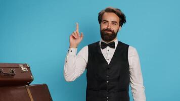 Hotel porter coming up with idea, looking for solution on camera against background. Formal luxury employee in suit acting like a genius and thinking about new answer to solve problem. photo