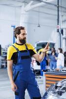 Expert in repair shop using augmented reality holograms to check car attributes during maintenance. Diligent garage employee using futuristic AR technology to examine unfunctional vehicle photo