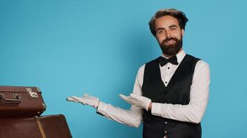 Doorkeeper shows left side in studio, wearing formal suit and tie while he does marketing ad to suggest direction sideways. Stylish classy hotel concierge worker presents advertisement. photo