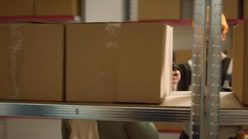 Focused warehouse employee and colleague scanning cardboard boxes on cabinet shelves, updating storage room merchandise labels info before sending parcels to be dispatched photo