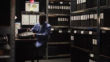 joven detective inspector con pericia en forense análisis investiga delincuente caso en incidente habitación. masculino policía oficial meticulosamente examina evidencia y archivos por utilizando moderno tecnología. foto