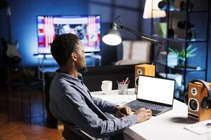 Freelancer looks at white screen on laptop while working remotely, using blank template on display and improving his skills at home. Developer enjoying self training course program. photo