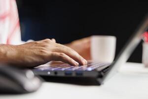 Selective focus on hands of a Middle Eastern individual typing and taking notes on a minicomputer while remaining wirelessly connected. Close-up of a person using a contemporary digital laptop. photo