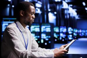 Technical support executive resolving performance related issues in data center mainframes. Manager utilizing mock up tablet to identify operational problems causing hardware slowdown photo