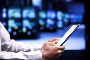 Experienced employee resolving performance related issues in data center mainframes. Admin utilizing mock up tablet to identify operational problems causing equipment slowdown photo