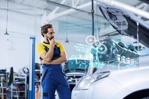 Mechanic in repair shop using augmented reality holograms to check car performance parameters during checkup. Adept garage employee using futuristic AR technology to examine damaged vehicle photo