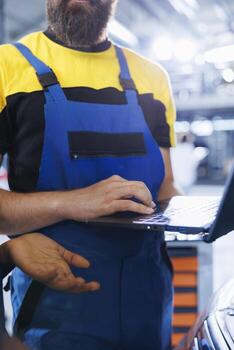 Mechanic in car service uses laptop to calculate invoice for client after repairing distributor. Qualified employee in garage with customer calculating final costs after servicing vehicle photo