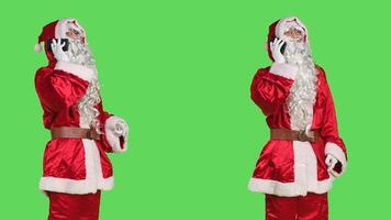 Man santa claus cosplay on phone call using remote chat on smartphone while he is wearing famous red and white costume. Saint nick character using mobile phone line to talk, greenscreen. photo