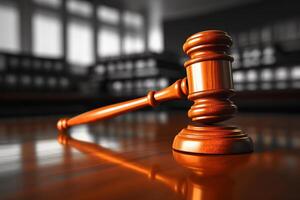A wooden judges hammer rests on top of a wooden table, in a legal setting. photo