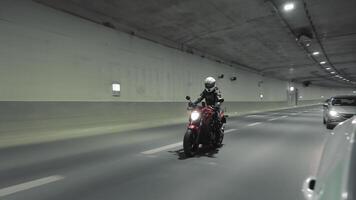 Motorcyclist riding in tunnel. A motorcyclist in full gear, including helmet and suit, rides a red motorcycle through a tunnel, emphasizing speed and adventure. video