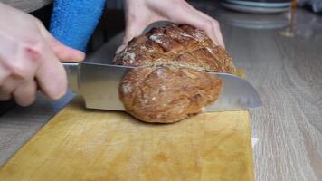 A GIRL CUTS BREAD ON A BOARD WITH A SHARP LARGE KNIFE. video