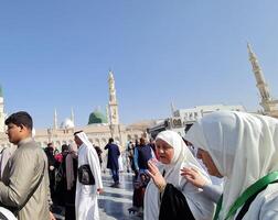 Medina, Saudi Arabia on March 1, 2024. Male and female Umrah pilgrims taking photos and walking in front of the tomb of the Prophet Muhammad at the Nabawi Mosque.
