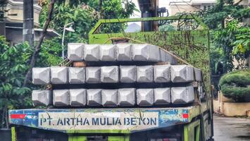 Bekasi, Indonesia on October 7, 2023. A small flat bed truck is transporting a pile of square pile or minipile material.. photo