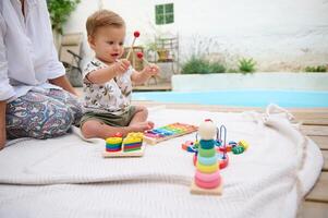Baby playing with colorful educational toys by the poolside photo