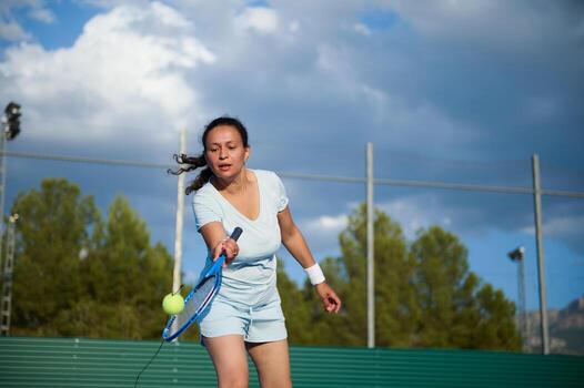 Woman playing tennis on an outdoor court under a cloudy sky photo