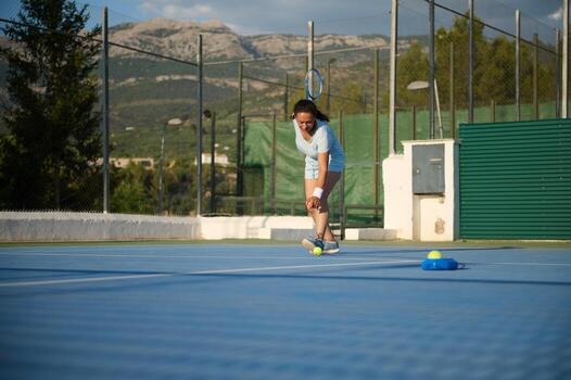 Woman playing tennis on outdoor court with mountains in background photo