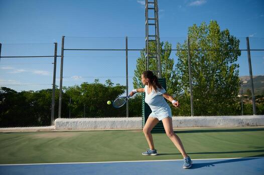 Young woman playing tennis on an outdoor court on a sunny day photo