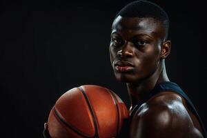 Portrait of a focused basketball player holding a ball against a dark background, showcasing determination and athleticism. photo