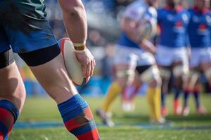 Close-up of rugby player holding ball during match, with teammates in the background on green field, blue and yellow uniforms. photo
