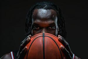 Intense portrait of a basketball player holding a ball against a dark background, showcasing focus and determination in sports. photo