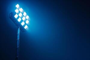 Bright stadium floodlight shining against a dark blue night sky, illuminating the scene with a strong, focused beam of light. photo