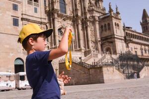 Child taking a photo of the view over the dam. Boy tourist with children's camera takes pictures of attractions during summer vacation