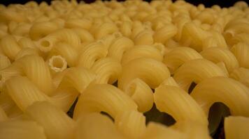 A close up shot of uncooked cavatappi pasta. The pasta is a pale yellow color and has a spiral shape. video