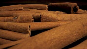 A pile of cinnamon sticks are shown in a close up shot. The sticks are stacked on top of each other, showcasing their rich brown color and textured surface. video