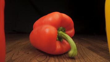 Red and yellow peppers on a wooden surface. The camera moves between the vegetables. Cooking concept. video