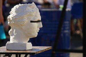 A plaster statue of the head of David with eyes taped with black tape. denial of reality photo