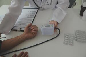 Doctor using sphygmomanometer with stethoscope checking blood pressure to a patient in the hospital. photo