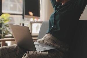 Distracted from work worried young woman sitting on couch with laptop, thinking of problems. Pensive unmotivated lady looking at window, feeling lack of energy, doing remote freelance tasks at home. photo