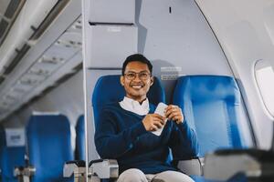 Man with dark hair is reading text message on mobile phone and speaking by phone during flying in the airplane photo