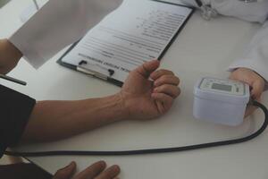 Doctor using sphygmomanometer with stethoscope checking blood pressure to a patient in the hospital. photo