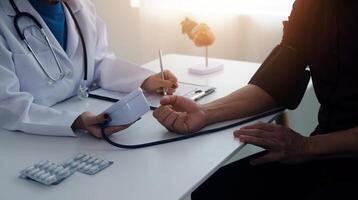Doctor using sphygmomanometer with stethoscope checking blood pressure to a patient in the hospital. photo