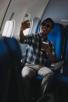 Traveling and technology. happy young businessman working on laptop computer and smartphone while sitting in airplane. photo