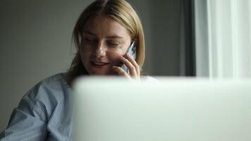 Business young female employee speaking on telephone and using app laptop at office workplace. Multitasking manager talking on mobile phone, making call to client, advisor giving consultation video