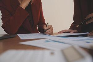 Group of confident business people point to graphs and charts to analyze market data, balance sheet, account, net profit to plan new sales strategies to increase production capacity. photo
