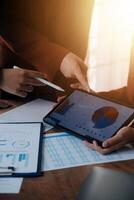 Group of confident business people point to graphs and charts to analyze market data, balance sheet, account, net profit to plan new sales strategies to increase production capacity. photo