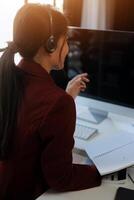 Friendly female helpline operator in call center. Young woman working in call center and holding microphone on headset with hand. photo