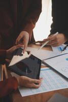 Group of confident business people point to graphs and charts to analyze market data, balance sheet, account, net profit to plan new sales strategies to increase production capacity. photo
