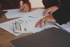 Group of confident business people point to graphs and charts to analyze market data, balance sheet, account, net profit to plan new sales strategies to increase production capacity. photo