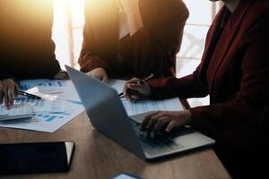 Group of confident business people point to graphs and charts to analyze market data, balance sheet, account, net profit to plan new sales strategies to increase production capacity. photo