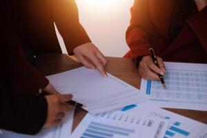 Group of confident business people point to graphs and charts to analyze market data, balance sheet, account, net profit to plan new sales strategies to increase production capacity. photo