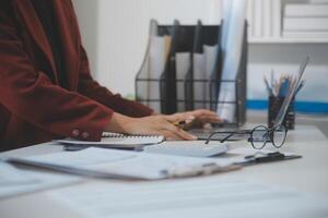 Cropped image of professional businesswoman working at her office via laptop, young female manager using portable computer device while sitting at modern loft, flare light, work process concept photo